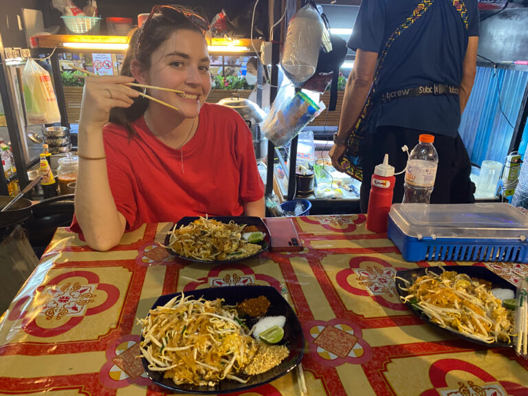 Frau isst Pad Thai auf dunklem Nachtmarkt auf der Khao San Road